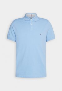 Polo bleu clair à manches courtes avec col à boutons et petit logo brodé rouge, blanc et bleu sur la poitrine gauche.