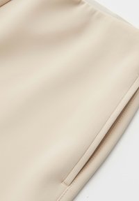 Beige fabric with a smooth texture, featuring a clean cut and a side zipper detail for closure.