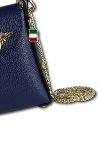 Sac en cuir bleu marine au design structuré, avec une bandoulière en chaîne dorée et une décoration en forme de papillon ; comprend un pendentif en forme de drapeau italien.