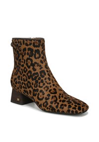 Bottines avec imprimé léopard en fausse fourrure, dotées d'un bout pointu et d'un talon empilé. Accent logo doré sur le talon. Nuance de couleurs marron et noir.