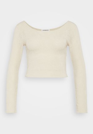 Krémový, dlouhý rukáv crop top s kulatým výstřihem, strukturovaná pletenina a mírně přiléhavý střih. Žádné viditelné kovové prvky.