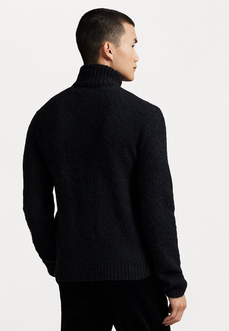 Pull en laine sombre avec col roulé, finition texturée, col et ourlet côtelés, offrant une coupe décontractée et des manches longues.