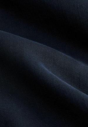 Tamsiai mėlynas audinys su lygia tekstūra, turintis įstrižų audimo raštų ir subtilų blizgesį. Dėmesys kreivėms ir šviesos atspindžiams.