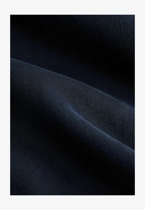 Sötétkék szövet sima textúrával, átlós szövésmintákkal és diszkrét fényességgel. A redők és a fényvisszaverődések kiemelésére fókuszálva.