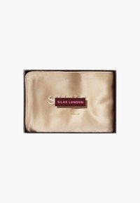 Funda de almohada de satén dorado exhibida en una caja rectangular, con una etiqueta que dice "SILKE LONDON" y "FUNDAS DE ALMOHADA DE SEDA PURA" en colores contrastantes.