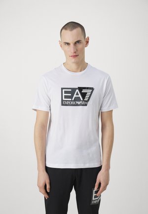 Biała bawełniana koszulka z krótkim rękawem z czarno-białym logo "EA7 EMPORIO ARMANI" z przodu. Model z okrągłym dekoltem.