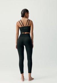 Czarny strój sportowy składający się z krótkiego topu na cienkich ramiączkach oraz legginsów z wysokim stanem, prezentujący texturedny materiał i detale szwów.