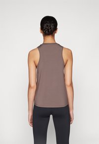 Top sans manches marron avec un col rond et une texture lisse, montré de dos, porté avec un legging noir.