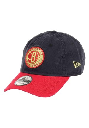 Adjustable cotton cap with a navy blue crown and red brim. Features an embroidered circular logo in gold and red on the front.