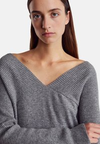 Šedý pletený svetr s výstřihem do V, s hřebeneckou texturou na krku a manžetách, a hladkým designem těla.