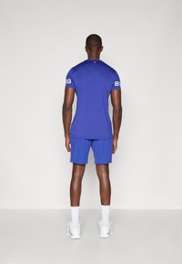 Roupa atlética masculina com uma camisa azul justa e calções a condizer. Feita de tecido respirável, com o logótipo "BORG" nas mangas da camisa.