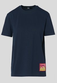 Tummansininen t-paita lyhyillä hihoilla, pyöreällä kaula-aukolla ja kirkasvärisellä kudotulla bränditarralla alaosassa. Pehmeä materiaali, normaali malli.