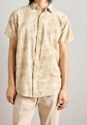Chemise à manches courtes boutonnée en beige avec un motif texturé de feuilles de palmier. Fabriquée en tissu léger, elle présente un col classique et une coupe décontractée.