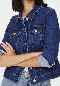 Mörkblå denimjacka med en figursydd design, knäppning fram, två bröstfickor och uppvuxna ärmar med en ljusblå denimuppvikning.