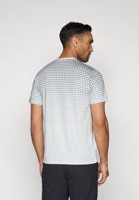 Witte t-shirt met korte mouwen, featuring een vervagend stippenpatroon op de bovenhelft, gemaakt van lichtgewicht stof, met een ronde halsontwerp.