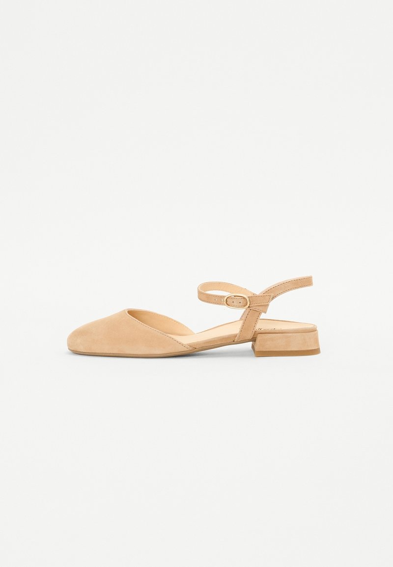 Chaussure slingback en daim beige avec un bout arrondi, un talon plat et une bride de cheville ornée d'une petite boucle. Texture lisse et design minimaliste.