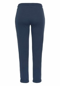Pantalones de chándal azul marino con cintura elástica, piernas ajustadas y puños enrollados. Fabricados con un tejido suave de textura lisa.