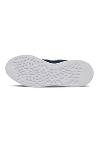 Sula av sko med en vit gummiyta, med ett geometriskt mönster för grepp och stabilitet. Mörk tygöverkant synlig vid den övre kanten.