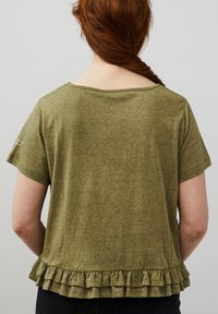 Olivgrön t-shirt med kort ärm, rundad halsringning och volangkant. Tillverkad av mjukt, strukturerat tyg. Endast bakvy.