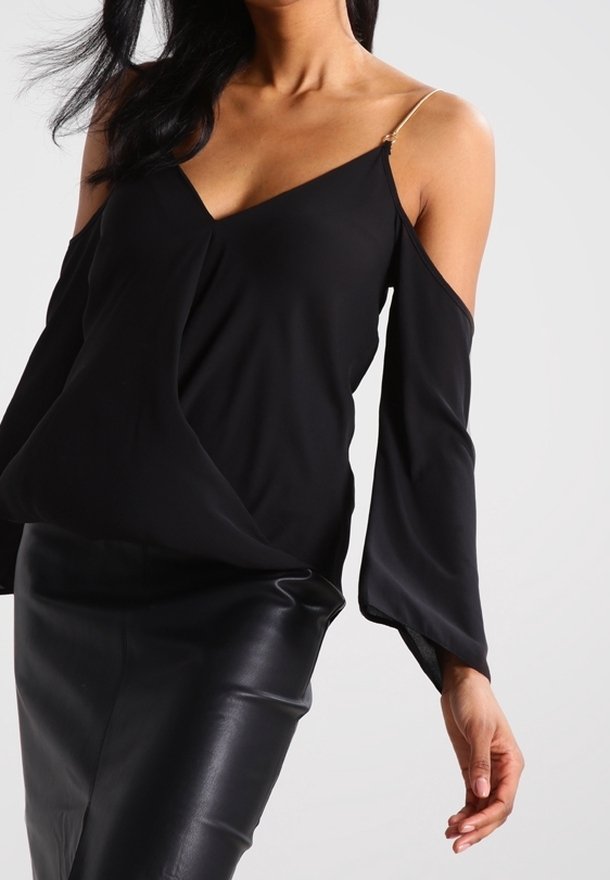 Svart avskuren topp med långa klockärmar, med en v-ringning och en slät yta. Matchas med en svart figurnära kjol.