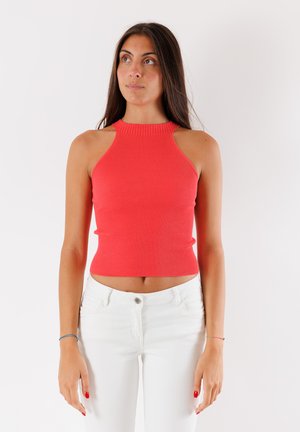 Top corto a halter rosso a coste con scollatura alta e spalle scoperte, abbinato a jeans bianchi a vita alta. Design semplice e aderente.