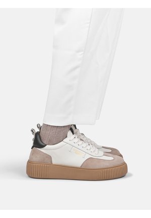 Schoenen gedragen met een witte broek en lichtbruine sokken, met witte, beige en zwarte sneakers met dikke bruine zolen.