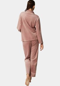 Roze pluche pyjamastel met een lange mouw top met een sjawl kraag en bijpassende broek met elastische taille, zachte textuur en een ontspannen pasvorm.