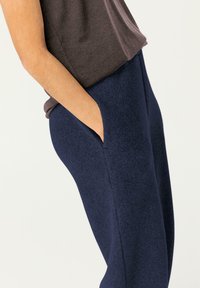 Marineblauwe sweatpants van een zachte, gestructureerde stof; voorzien van zijzakken en een licht toelopend ontwerp. Gepaard met een donkergrijze top.