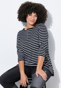 Zwart-wit gestreepte lange mouwen top met een ronde halslijn en een relaxte pasvorm, gecombineerd met donkerdenim; zachte textuur en casual ontwerp.