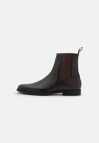 Brązowe skórzane botki za kostkę z elastycznymi bokami i uchwytem do zakupu. Elegancki design, okrągły nosek i płaska gumowa podeszwa.