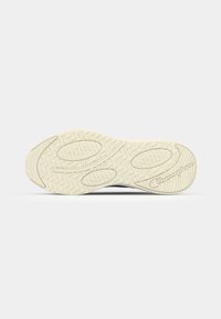 Shoe sole featuring a textured rubber design in cream color with an engraved brand logo. The pattern includes wavy and circular elements.