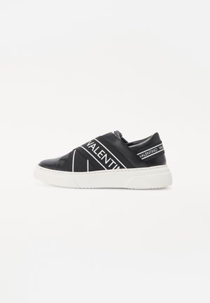 Zapatilla negra tipo slip-on con suela blanca gruesa y tiras elásticas que llevan la marca "VALENTINO" en el lateral y el talón.