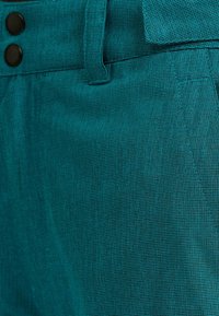 Teal textured shorts med ett subtilt vävt mönster, två svarta knappar vid midjan och en klassisk skräddad design.