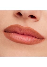 Matte naken läppstift på släta, fylliga läppar med en subtil lyster. Färgen övergår från mörk naken vid kanterna till ljus naken i mitten.