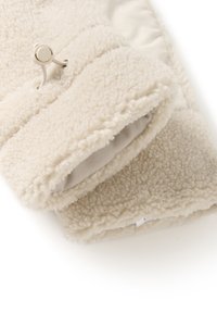 Mânuși din fleece de culoare crem, cu o textură pufoasă, având o livrea interioară netedă și o închidere cu șnur pentru o ajustare sigură.