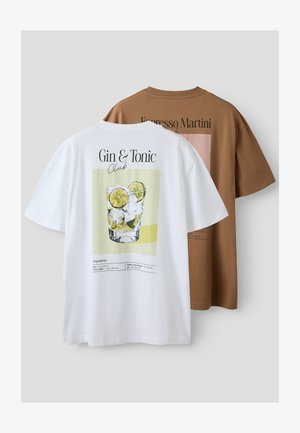 Camisetas blancas y marrones con recetas de cócteles impresas en la parte trasera; la blanca muestra ginebra y tónica con ilustración de lima y hielo.