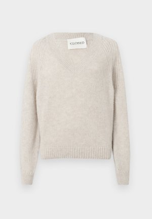 Lys beige strikkegenser med v-hals og stripete mansjetter. Har en myk tekstur og et subtilt mønster langs ermmene. Merkelapp synlig.