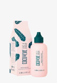 Roze 100ml Coco & Eve haarelixerfles met groene dop naast een bijpassende doos versierd met groene tropische bladdesigns.