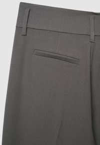 Pantaloni grigi con un materiale testurizzato, dotati di una singola tasca posteriore e passanti per cintura in vita. Design semplice e sartoriale.
