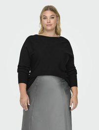 Melna adīta džemperis ar plašu laivu formas kaklu un garām piedurknēm, kombinēts ar spīdīgu pelēku satīna svārku. Gluda tekstūra, brīvs piegriezums.