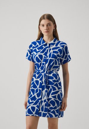 Sininen ja valkoinen lyhythihainen mekko, jossa on geometrinen kuvio, kaulus, nappikiinnitys ja vyö laskostetun vyötärön ympärillä.