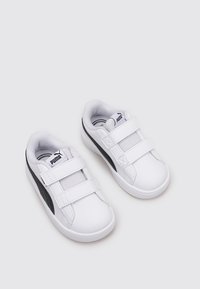 Sneakers bianche con materiale in rete e sintetico, dotate di due fibbie in velcro, una striscia nera laterale e punta rotonda.