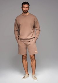 Beige Sweatshirt und Shorts aus Baumwollmischung, mit lockerer Passform, gerippten Bündchen und einem kleinen Markenetikett an der Seite.