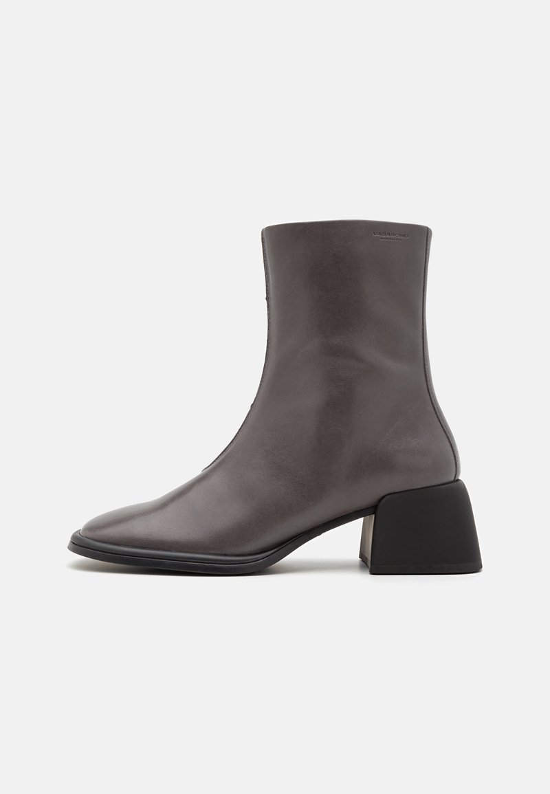 Botte cheville en cuir gris foncé avec bout carré et talon bloc noir épais, embossage visible de la marque près du bord supérieur.