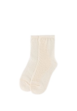 Par de calcetines tobilleros de punto color crema con una textura sutilmente acanalada y con patrón, mostrados planos sobre un fondo blanco.