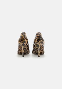 Chaussures à talons hauts en imprimé léopard avec une finition brillante, un bout pointu et un talon stiletto fin ; fabriquées en matériau synthétique.