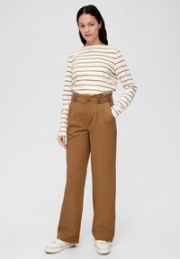 Gestreepte witte en bruine lange mouwen shirt in combinatie met hoge bruine wijde broek met een dubbel-knoopontwerp. Witte sneakers.