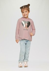 Roze hoodie met een hartvormige zilveren print waarop een hond staat en de tekst "Laten we vrienden zijn," gecombineerd met lichtblauwe jeans en roze sneakers.