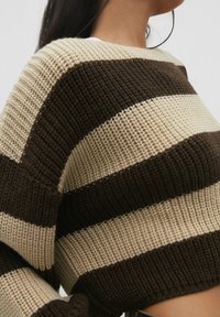 Brown and cream striped knitted sweater with a cropped design and ribbed texture. Features wide sleeves and a relaxed fit.