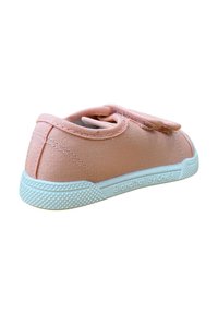 Zapatilla de lona rosa con una suela de goma blanca texturizada y un suave collarín en el talón. Cuenta con una correa de Velcro para un fácil ajuste.